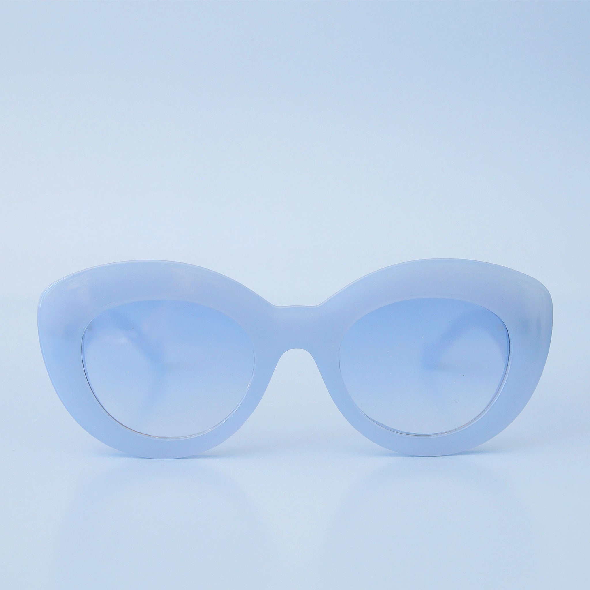 On a blue background is a model wearing the Gemma Sunglasses in the shade Lapis.