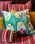 A green square pillow with red, yellow and pink floral print.