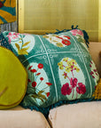 A green square pillow with red, yellow and pink floral print.