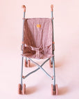 A pink and dark pink gingham printed stroller for dolls with pink wheels.