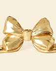 A gold bow shaped taper candle holder.