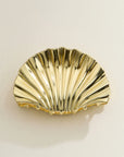 A gold seashell shaped hair clip.