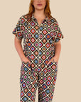 A multi-colored short sleeve jumpsuit with a zipper up the front and a floral pattern.