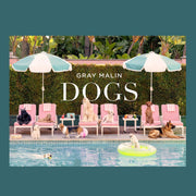 A book cover with a photo of different breeds of dogs sitting by a pool with umbrellas.