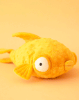 On a yellow background is a yellow stuffed toy fish with puffy eyes and lips.