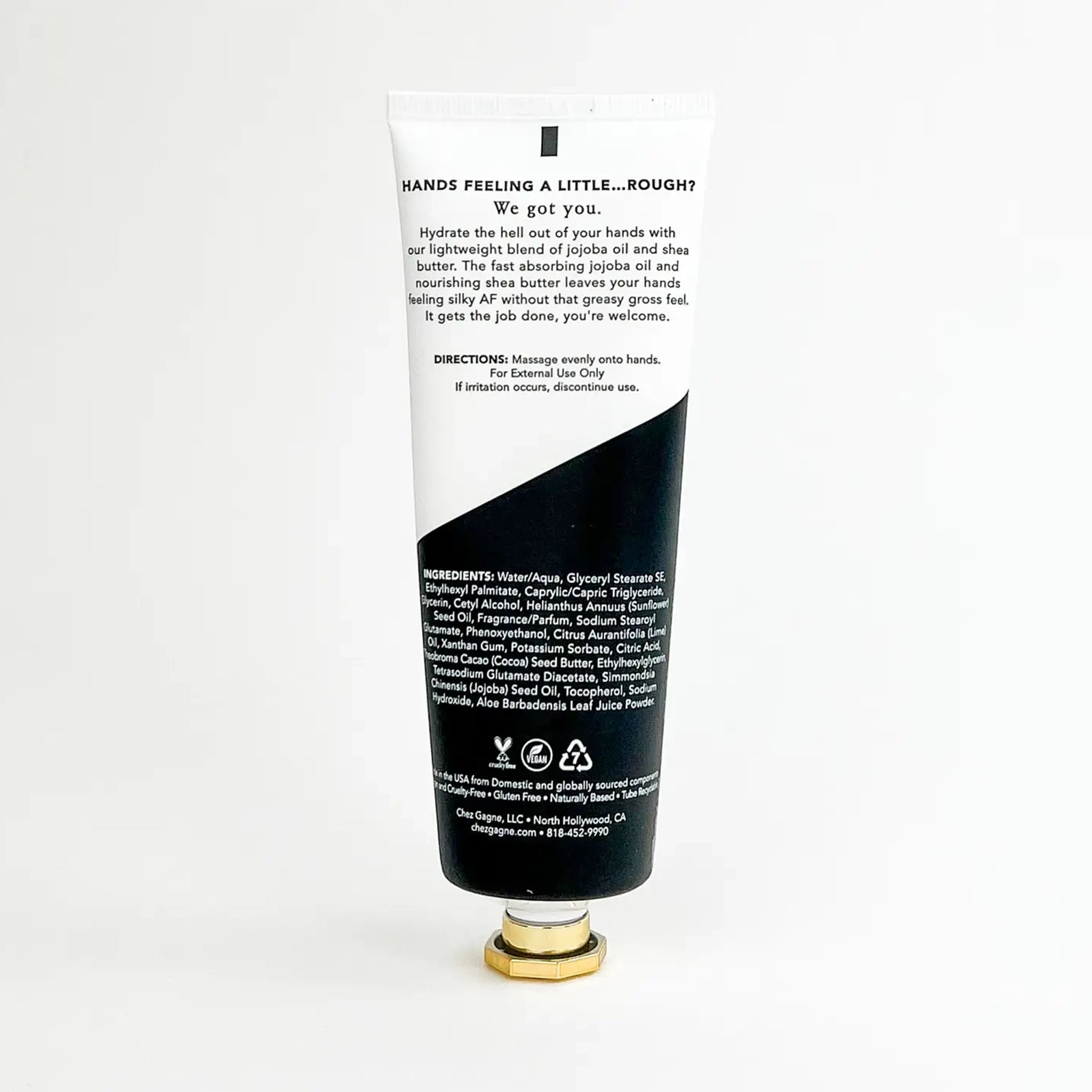 On a white background is a tube of hand cream that is half black and half white. This photo is the back of the tube that includes the list of ingredients as well as a little blurb about the moisturizer. 