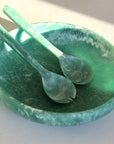 A green resin shallow serving bowl with a set of salad servers.