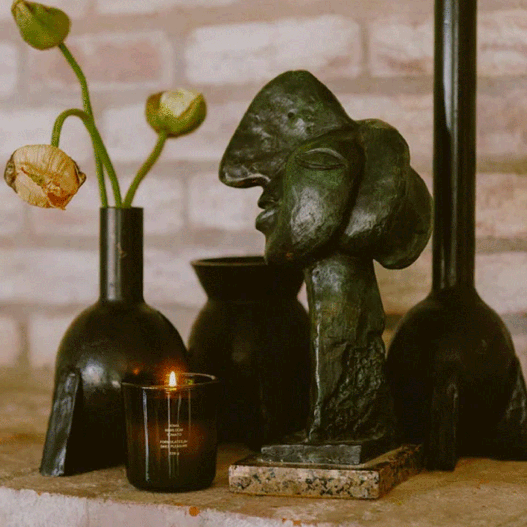A green glass candle surrounded with other green figurines and vases. 