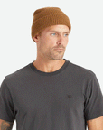 On a white background is a tan knit beanie with a label on the front cuff that reads, "Brixton".