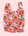 On a white background is a pink nylon bag with hello kitty and apple designs all over.