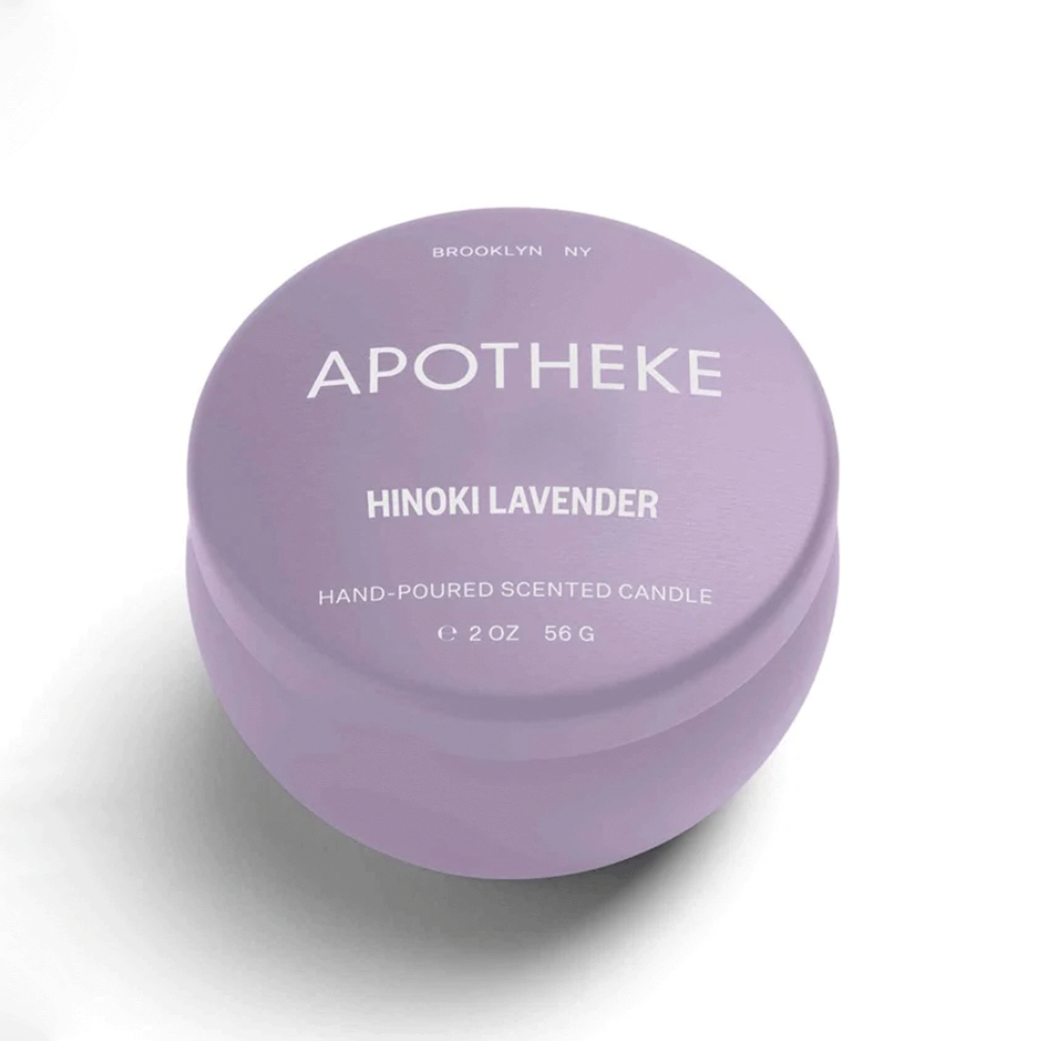 On a white background is a lavender mini tin circle candle with white text on the front that reads, &quot;Apotheke Hinoki Lavender Hand Poured Scented Candle&quot;. 
