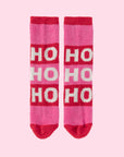 A pair of pink and red fuzzy socks that read, 'Ho Ho Ho' in white text down the front.