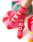 A pair of pink and red fuzzy socks that read, 'Ho Ho Ho' in white text down the front.