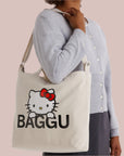 A neutral canvas bag with a shoulder strap and a screen printed Hello Kitty and black BAGGU logo.