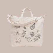 An ivory canvas bag with black shell embroidery.