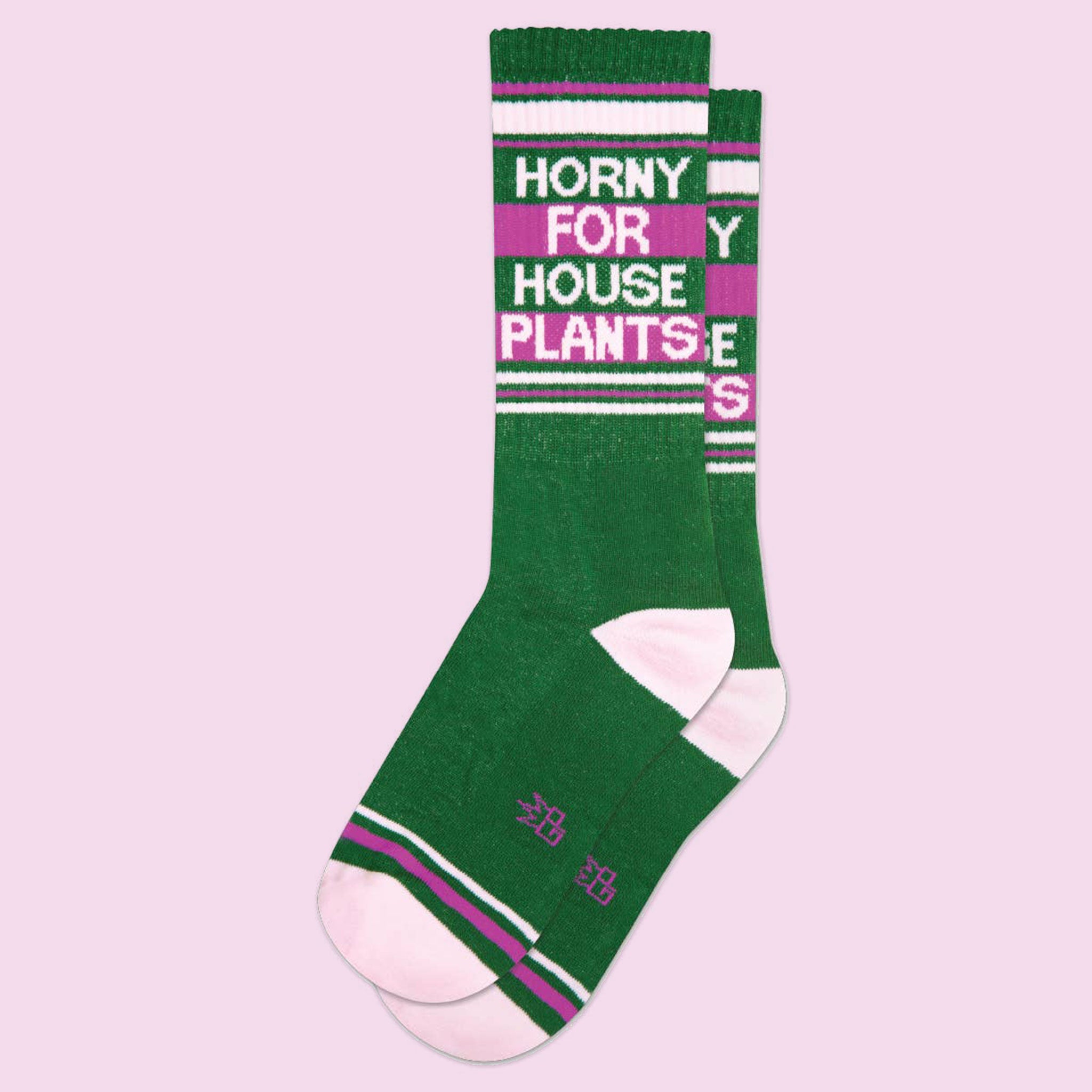 A green and bright pink pair of socks with white text that reads, "Horny For House Plants"