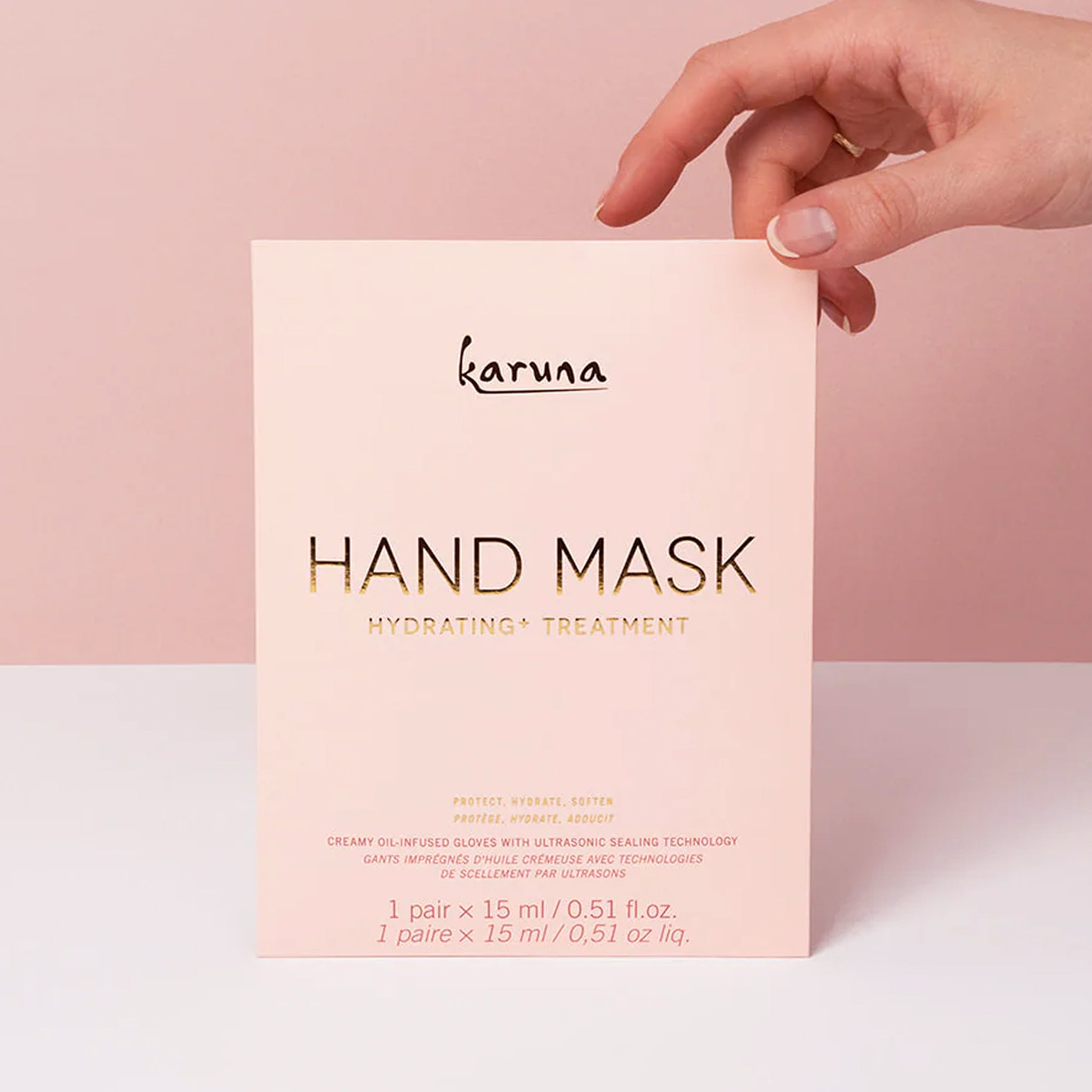 A pink packet with a hand mask inside that reads, &quot;Karuna Hand Mask Hydrating + Treatment&quot;.