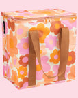 On a pink background is a orange pink and ivory floral print cooler bag.