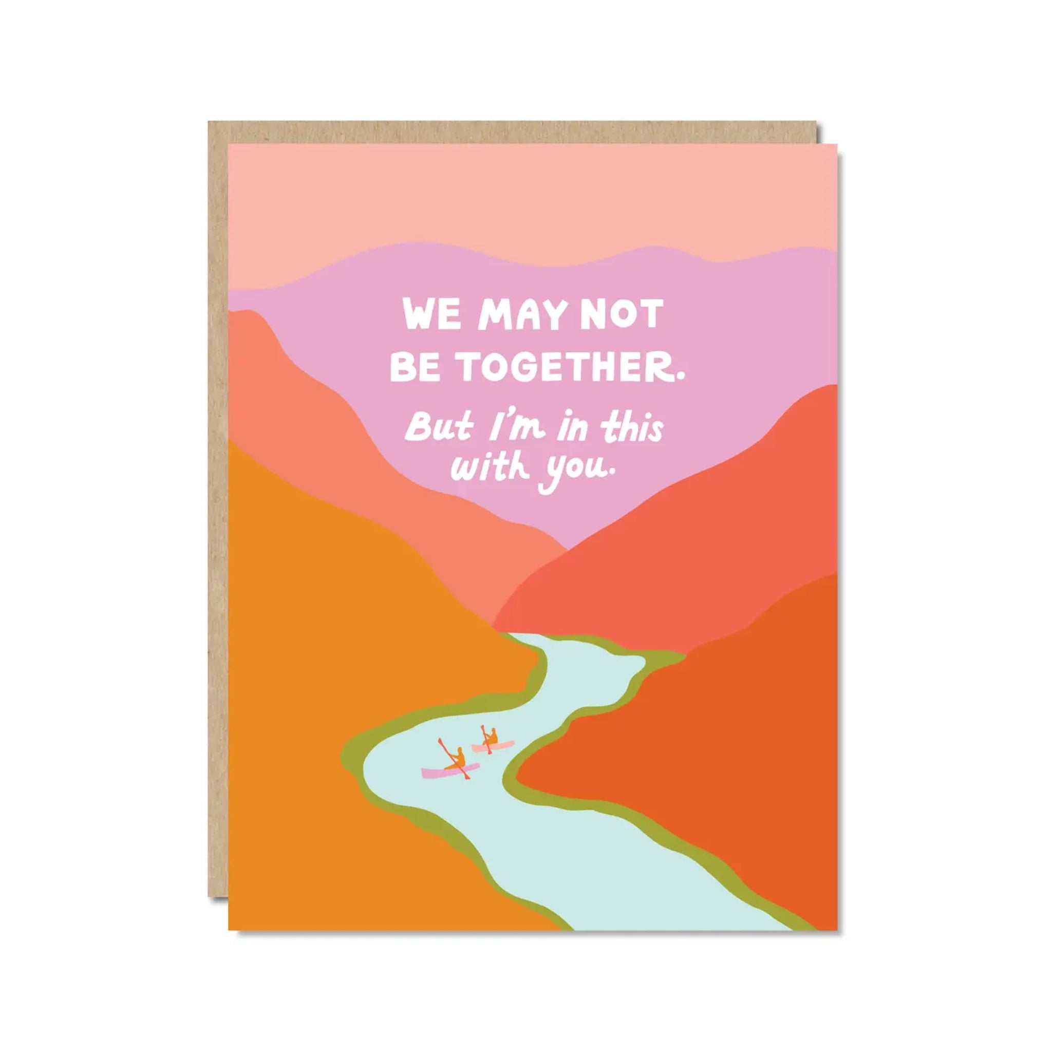 On a white background is a vibrant card with shades of orange, red, pink and purple making up a mountainous range with a river running through it along with white text at the top of the card that reads, "We May Not Be Together But I'm In This With You". 
