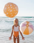 Two inflatable beach balls, one yellow floral printed and the other pink, yellow and white stripes.