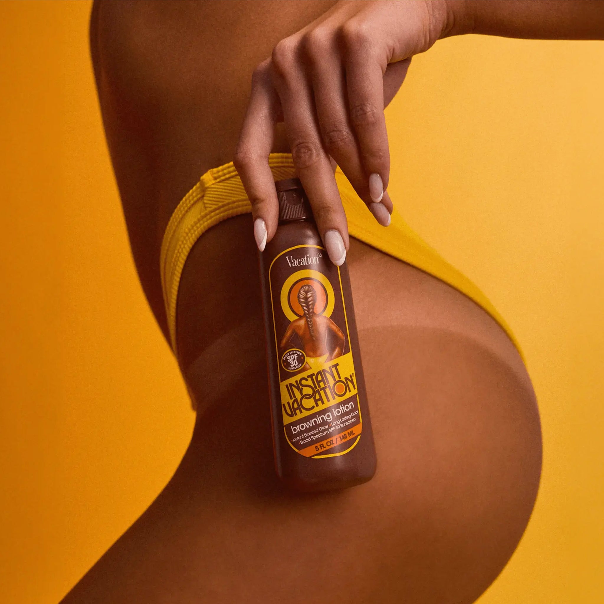 A model holding a bottle of tanning lotion. 