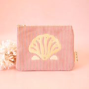 A light pink corduroy pouch with a zipper closure and an orange shell embroidered design in the center.