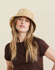 An ivory and tan bucket hat worn on a model.