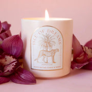 A neutral candle with an arched label with a cheetah and palm tree graphic and text that reads, 'Isle of Dreams'.