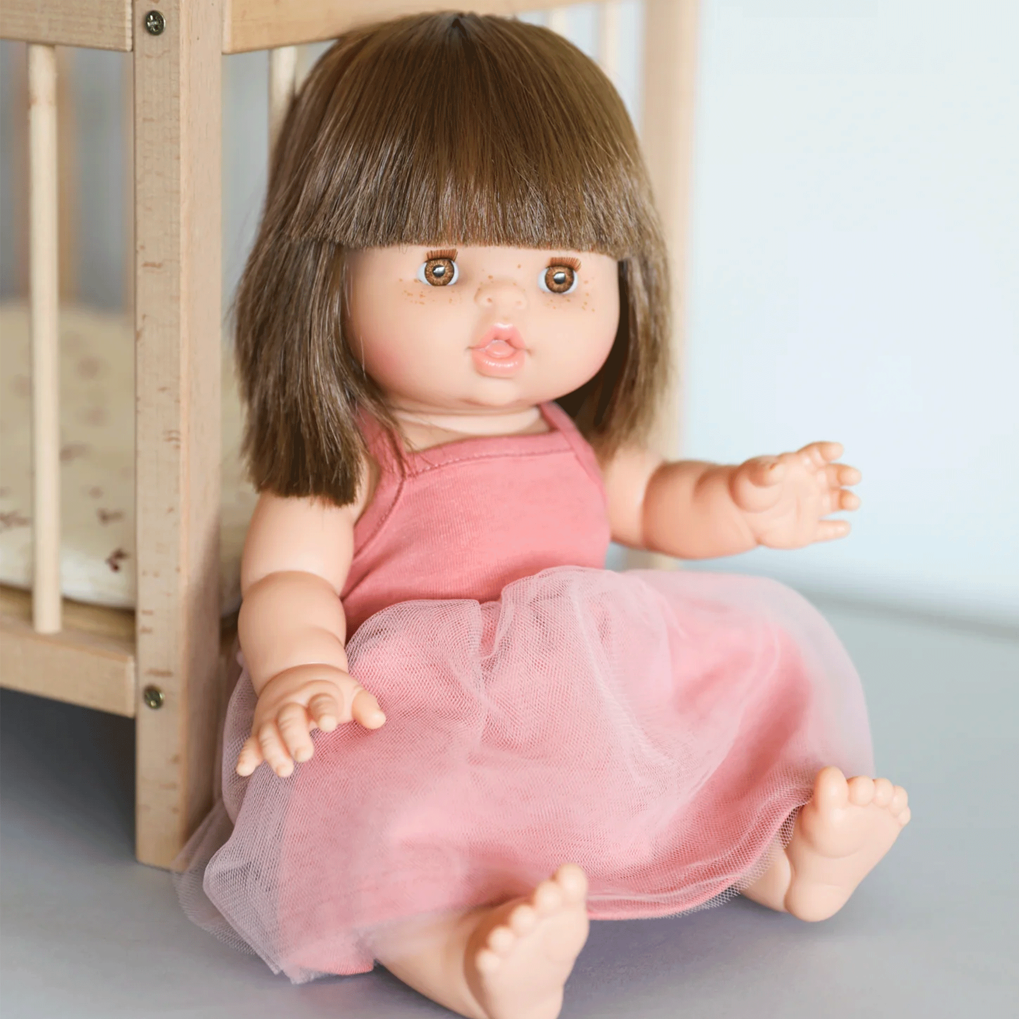 A baby doll with brown straight hair and amber colored eyes.