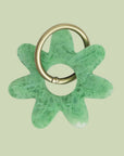 A light green flower shaped resin keychain with a silver loop for hanging.
