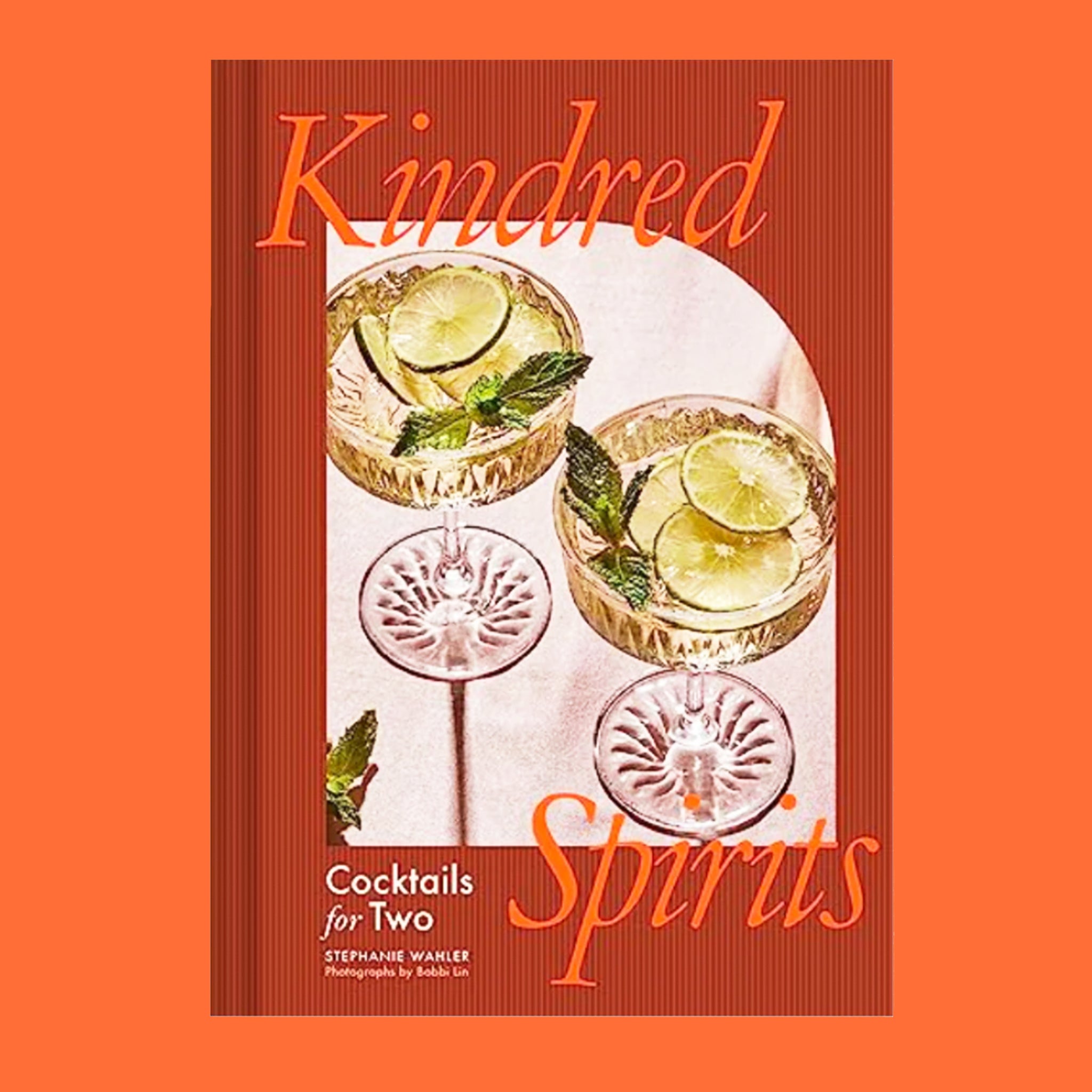 A burnt reddish orange book cover with a photograph of two beverages in coupe glasses and the title that reads, &quot;Kindred Spirits&quot;.