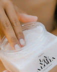 A clear container with a neutral body scrub inside, white lid and black text that reads, "La Vie Aloha".