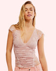 A lacey light pink cami tank top with ruffle details and a v-neck.