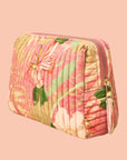 A coral and green floral patterned cosmetic pouch with a zipper closure.