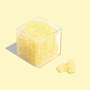 A clear acrylic box of yellow lemon drop flavored gummy bears. 