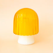 A white and yellow mushroom shaped candle with the "mushroom head" used as the lid.