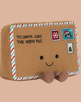 A brown letter shaped stuffed toy with a smiling face and brown legs and feet and text on the top left that reads, 'To Santa Claus The North Pole'.