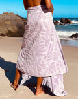 A light purple towel with a subtle floral print and fringe edge