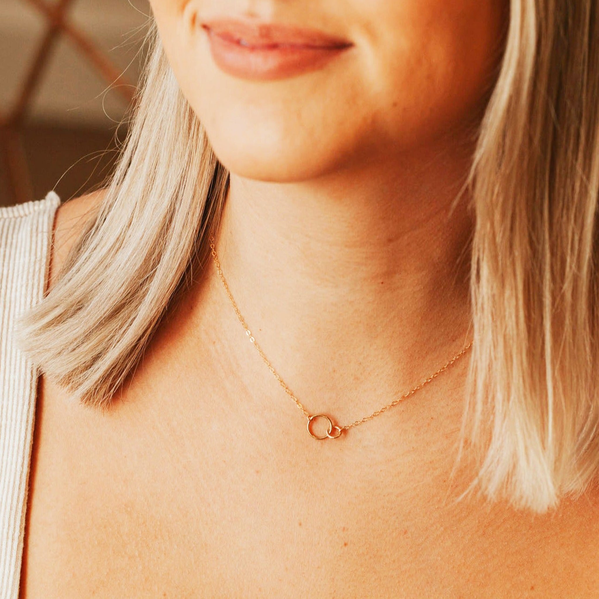 A dainty gold chain necklace with two different sized circle links connecting in the center.