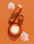 A lip duo of an orange jar of lip scrub and a tube of lip balm.