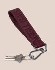A loop mahogany colored keychain with "BAGGU" on it.
