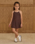Little girl wearing a black and brown leopard print dress with thin straps.