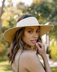 A neutral woven sun hat / visor with a white brim and a cut out at the top for your head to sit through.
