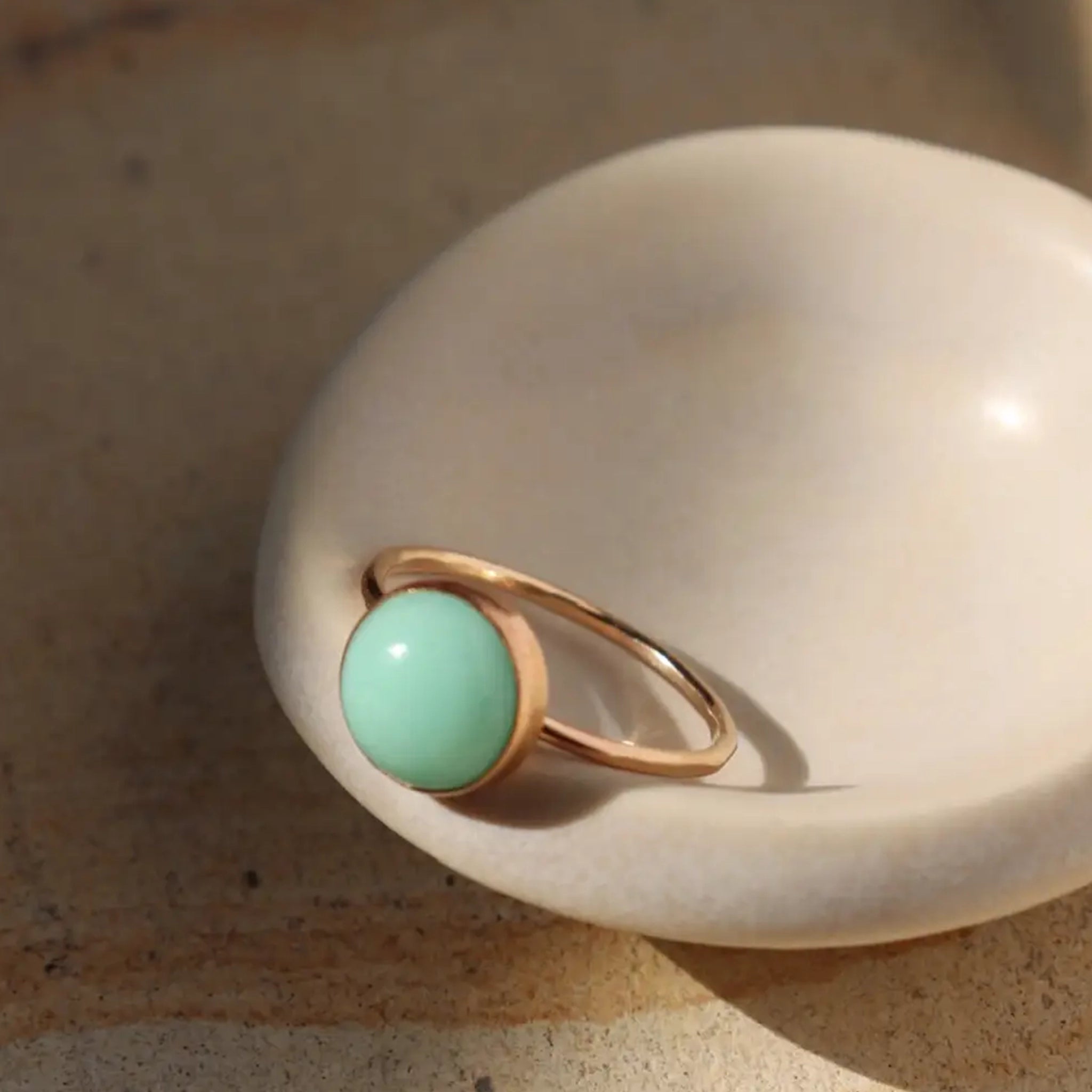 A thin gold ring with a green chrysoprase stone in the center. 