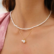 A gold chain necklace with a pearl and gold starfish pendant charm.