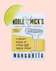A tangerine and white packet of margarita mix with the title, "Noble Mick's Single Serve Craft Cocktails" along with a drawing of a margarita and their mascot which is a moose.