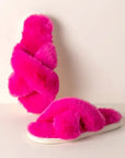 A pair of pink fuzzy slippers with a criss cross strap.