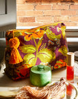 A green, dark purple and orange cosmetic bag with a floral print and a tassel as the zipper.
