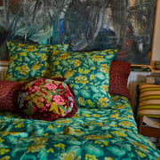 Green floral linen euro pillows shown on a bed.