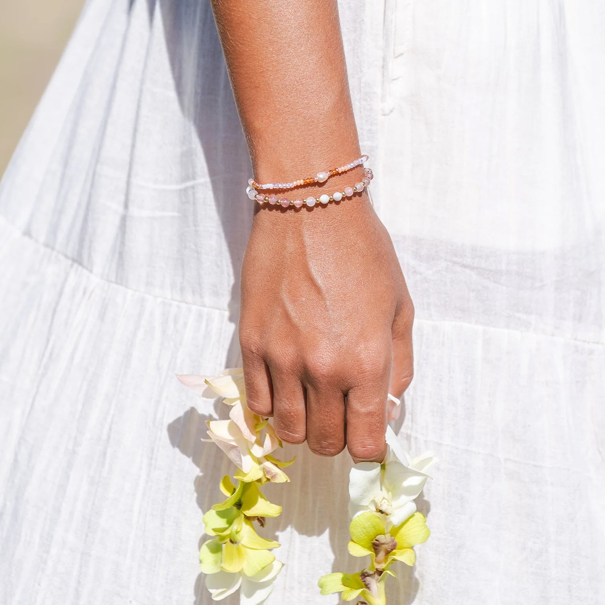 A peachy and white beaded bracelet with an adjustable cord detail.